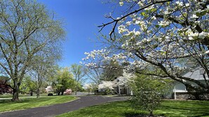 A residential street with a curved driveway, houses, and blooming trees. - Exquisite, first floor stone ranch Gettysburg large kitchen/living area - quiet  (Gettysburg)