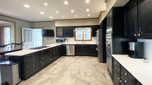 A modern kitchen with dark cabinetry, a large island, and a dishwasher. - Exquisite, first floor stone ranch Gettysburg large kitchen/living area - quiet  (Gettysburg)