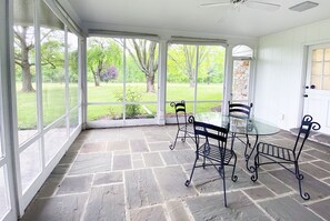 A covered patio with a glass table and metal chairs, stone flooring, and a view of a grassy garden. - Exquisite, first floor stone ranch Gettysburg large kitchen/living area - quiet (Gettysburg)
