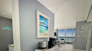 Ett kök med en kaffebryggare, en inramad tavla och en skylt med texten ”Välkommen till strandhuset”.