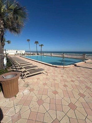 Un espace piscine avec des chaises longues, un jacuzzi et une vue sur l’océan.