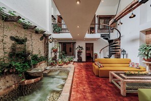 A spacious atrium with a central water feature, a yellow sofa, and a spiral staircase.