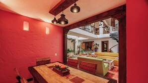 Un comedor con una mesa y sillas de madera, un sofá amarillo y una escalera que sube a un nivel superior.