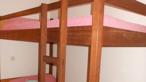 Een stapelbed met roze beddengoed en een ladder.