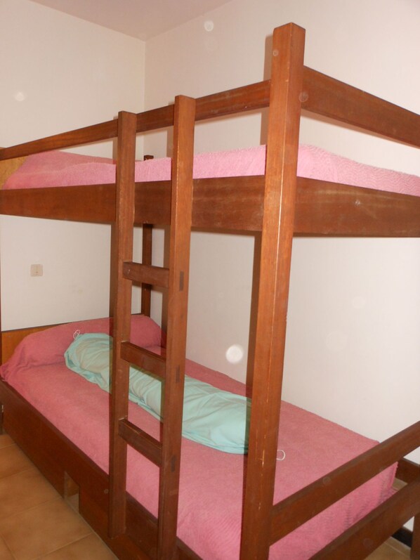 Een stapelbed met roze beddengoed en een ladder.