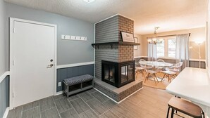 Una sala de estar acogedora con chimenea, un comedor con mesa y sillas, y un banco junto a la puerta.