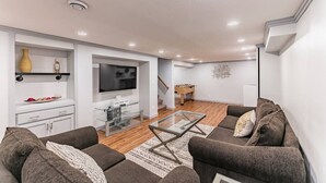 Una sala de estar moderna con un juego de sofá, una mesa de centro de vidrio y un televisor de pantalla plana.