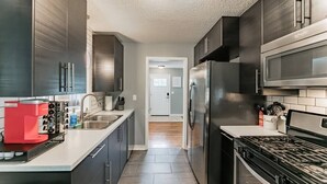 Una cocina moderna con armarios oscuros, electrodomésticos de acero inoxidable y una isla central.