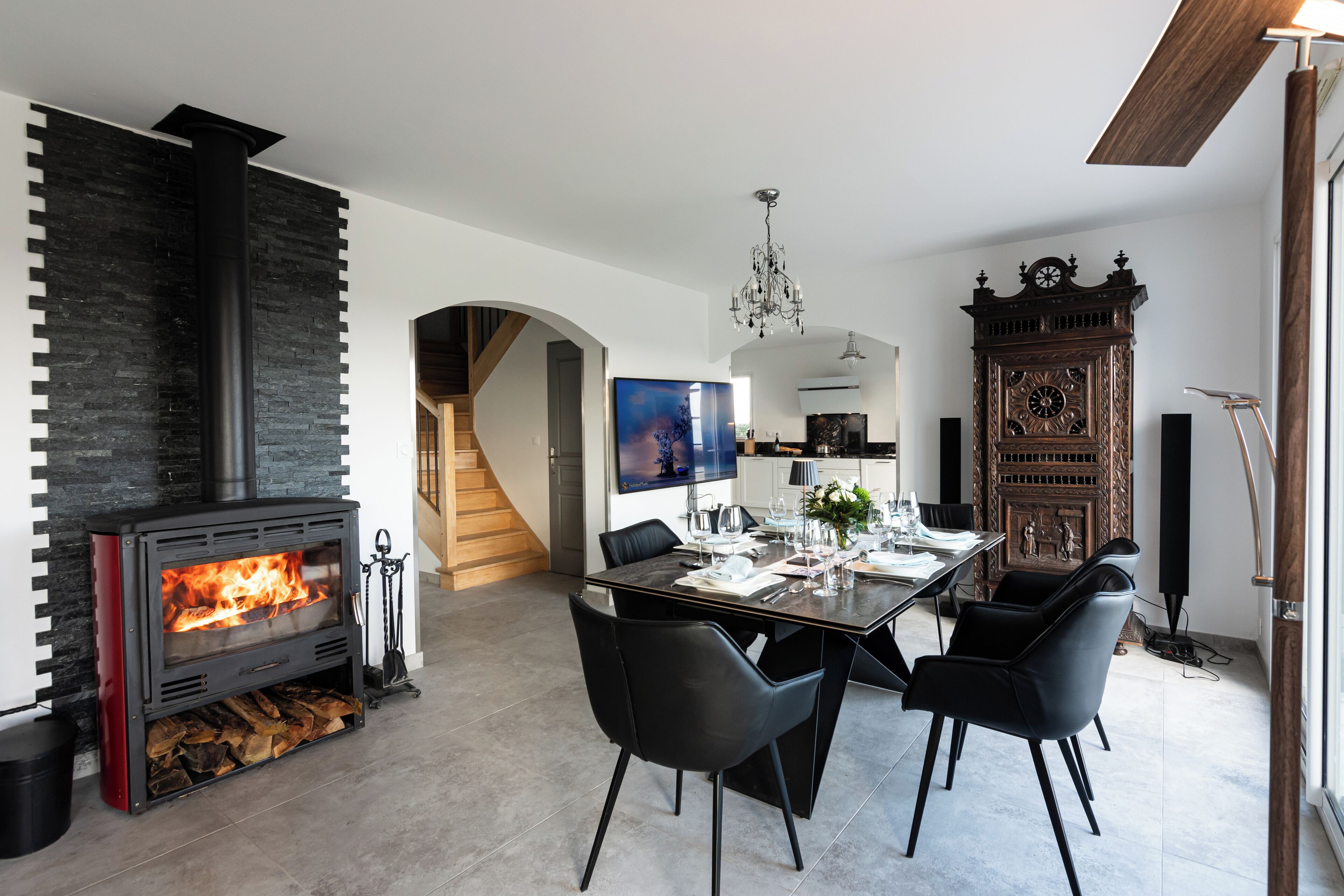 Un salon moderne avec une cheminée, une table à manger, des chaises et un grand meuble en bois.