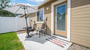 A patio with a table and chairs, a covered umbrella, and a door with a 'Please wipe your feet' mat. - Townhouse near College of Idaho, workspace (Caldwell)