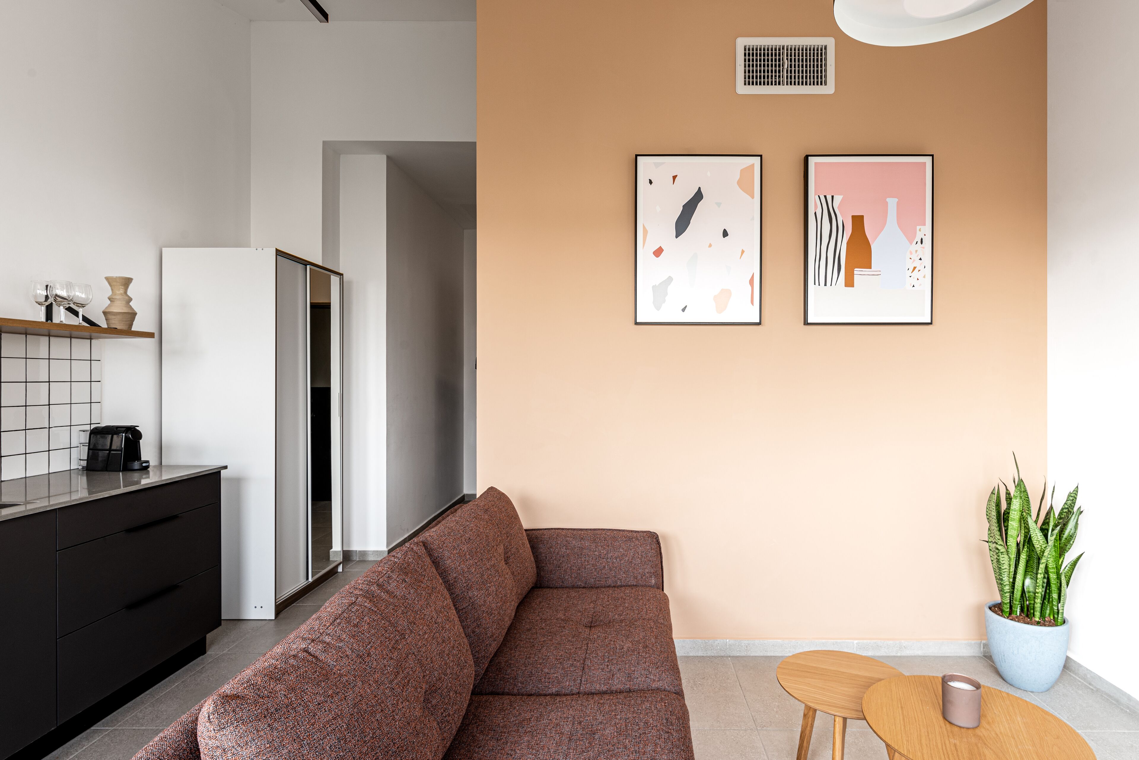 A modern living space with a brown sofa, a small wooden table, and a potted plant.