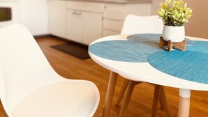 A modern kitchen with white cabinets, a wooden floor, and a dining table with chairs.