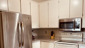 A modern kitchen with stainless steel appliances, white cabinets, and a wooden floor.