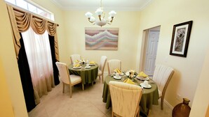 A dining room with a table set for four, a chandelier, and a painting on the wall. - SERENITY Vacation Home • Heated Pool • Sleeps 12 (Port St. Lucie)