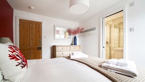 Une chambre à coucher comprenant un lit, une commode, un miroir et une porte donnant sur une salle de bain.