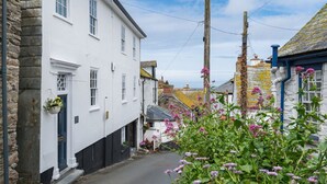 Une rue étroite bordée de bâtiments blancs, avec un lampadaire et des plantes en fleurs.