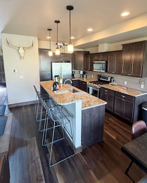 A modern kitchen with a central island, stainless steel appliances, and dark wood cabinetry.