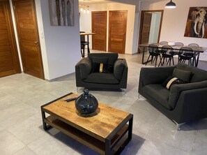 Un salon moderne comprenant deux canapés, une table basse et un coin repas avec des chaises et une table.