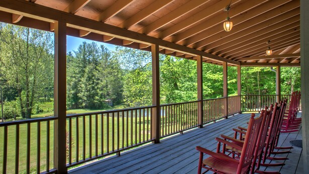 A covered porch with wooden railings and rocking chairs.