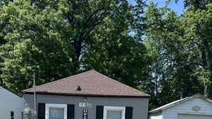 A small, single-story house with a dark roof and white trim. It has a 'WELCOME' sign on the side and a garage door. - COZY COTTAGE NEAR CEDAR POINT/ KALAHARI /SUMMIT RACEWAY (Norwalk)
