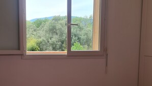 Ein Schlafzimmer mit großem Fenster, einer rosa Bettdecke und Holzböden.