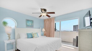 Ein Schlafzimmer mit einem Bett, einem Deckenventilator, einem Fenster und Blick ins Freie.