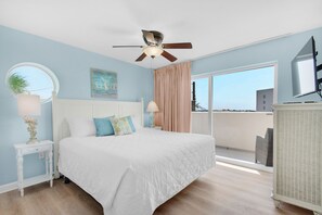 Un dormitorio con cama, ventilador de techo, ventana y vistas al exterior.