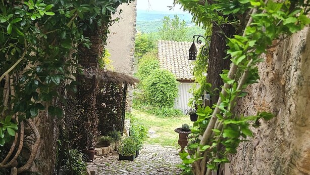 A stone pathway leading through a rustic stone archway surrounded by lush greenery.