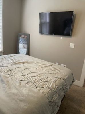 Relax in this serene bedroom with a comfortable bed, flat-screen TV, and stylish mirror.