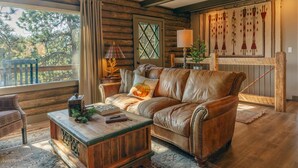 Un salon chaleureux avec un canapé en cuir, une table basse en bois et une grande fenêtre agrémentée de rideaux.
