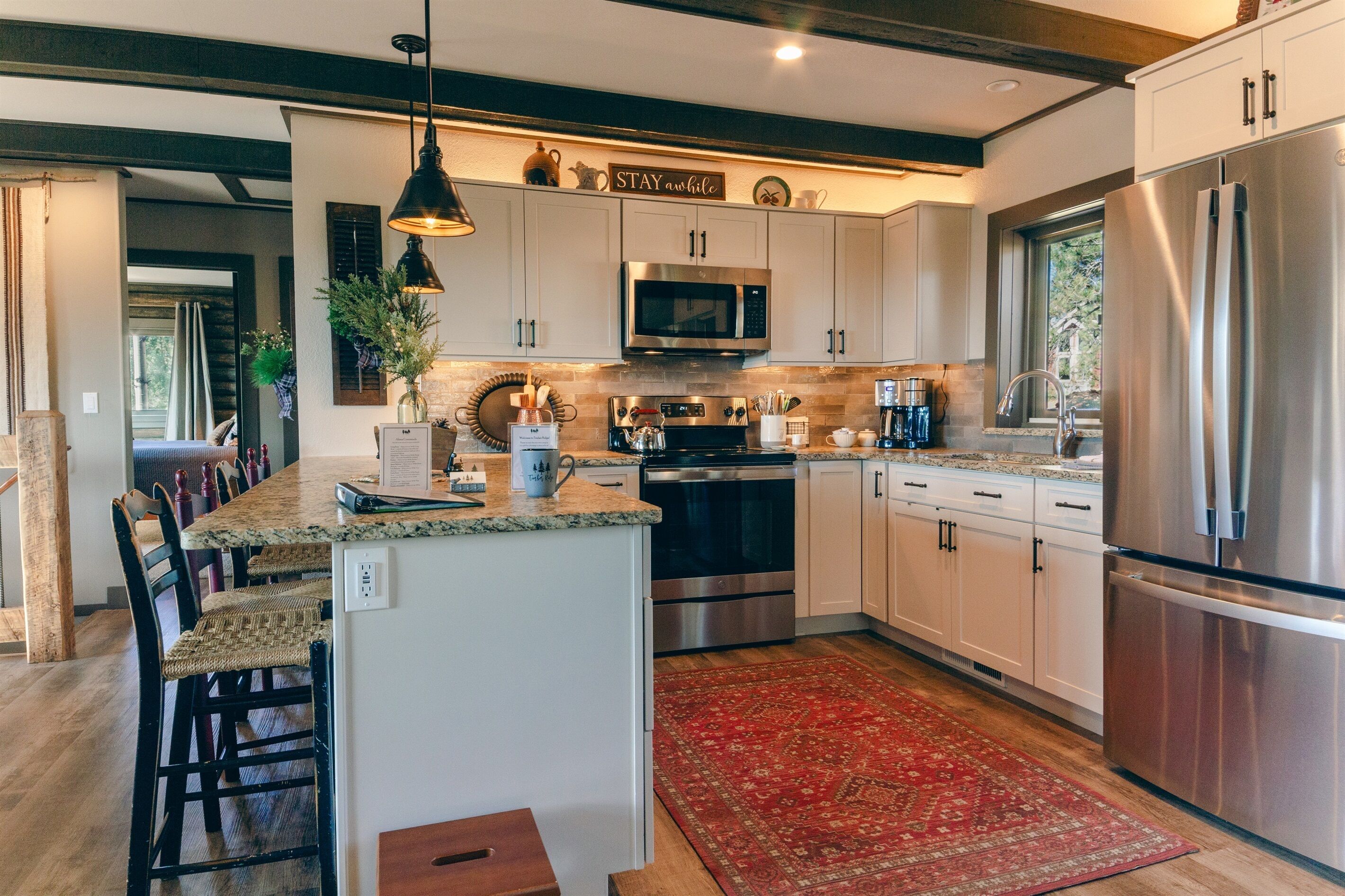 A modern kitchen with white cabinets, stainless steel appliances, and a central island with bar stools.