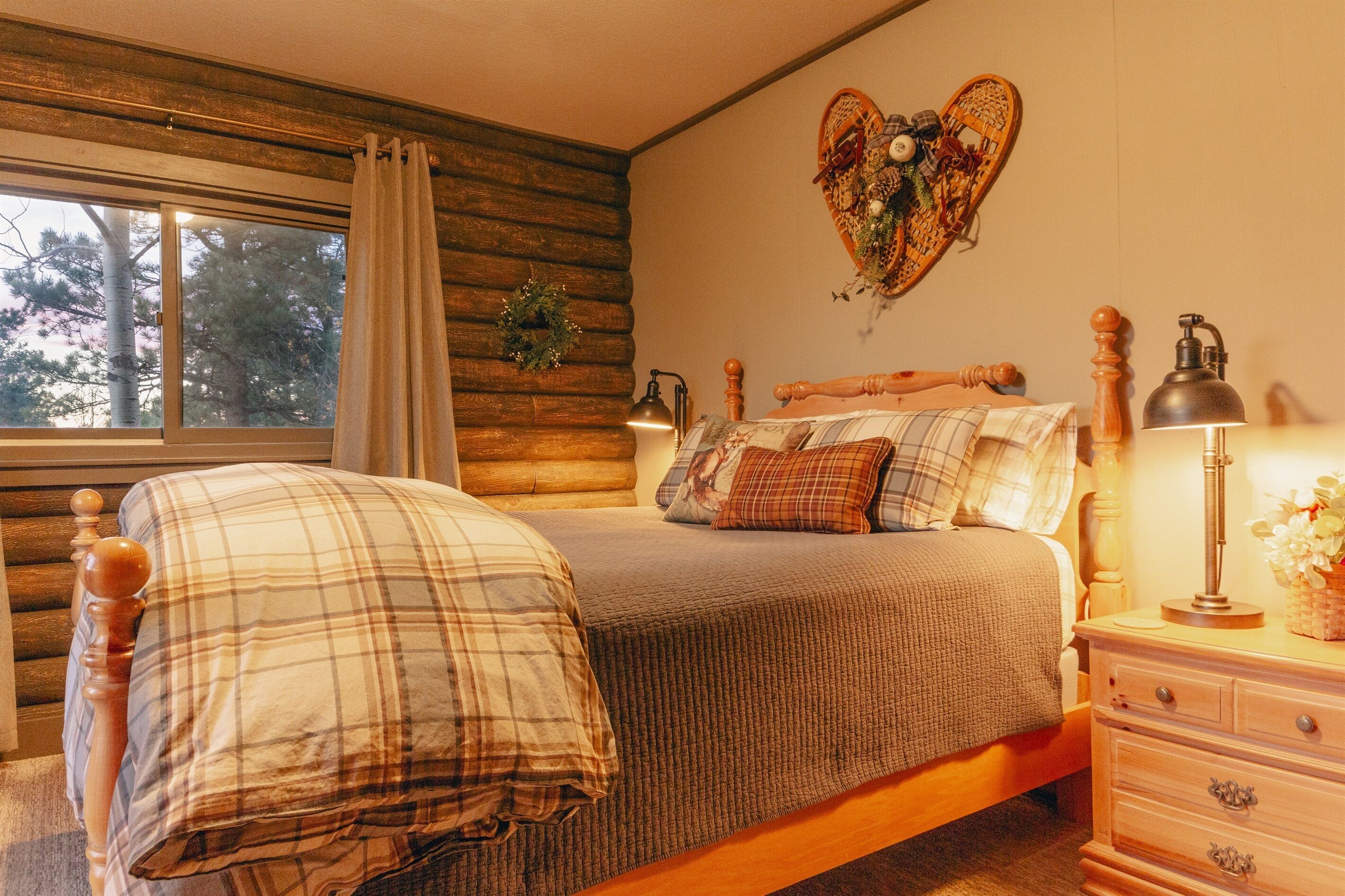 Een gezellige slaapkamer met een houten bed, een nachtkastje met een lamp en een decoratieve hartvorm aan de muur.