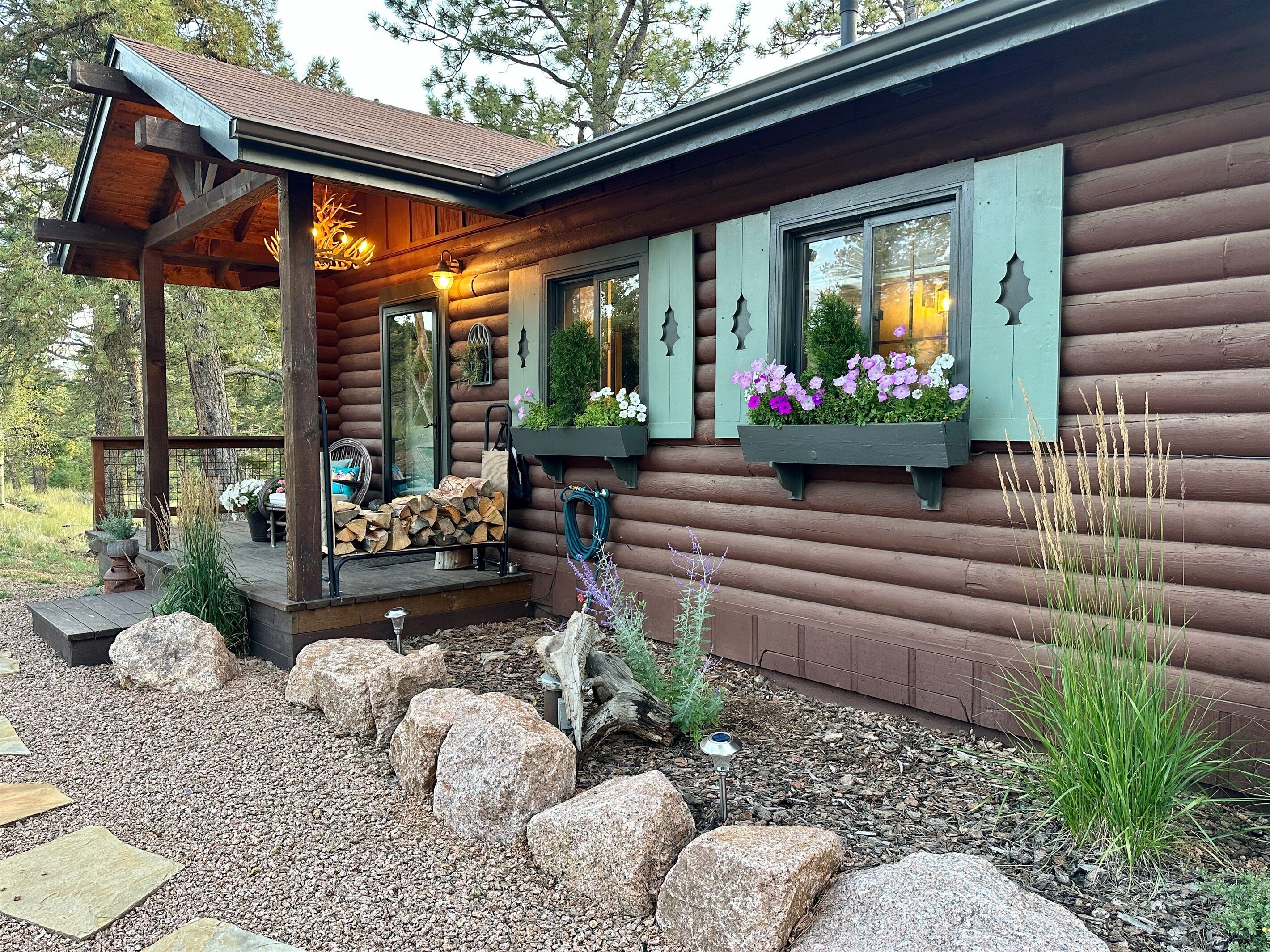 A log cabin with a porch, outdoor seating, and flower boxes.