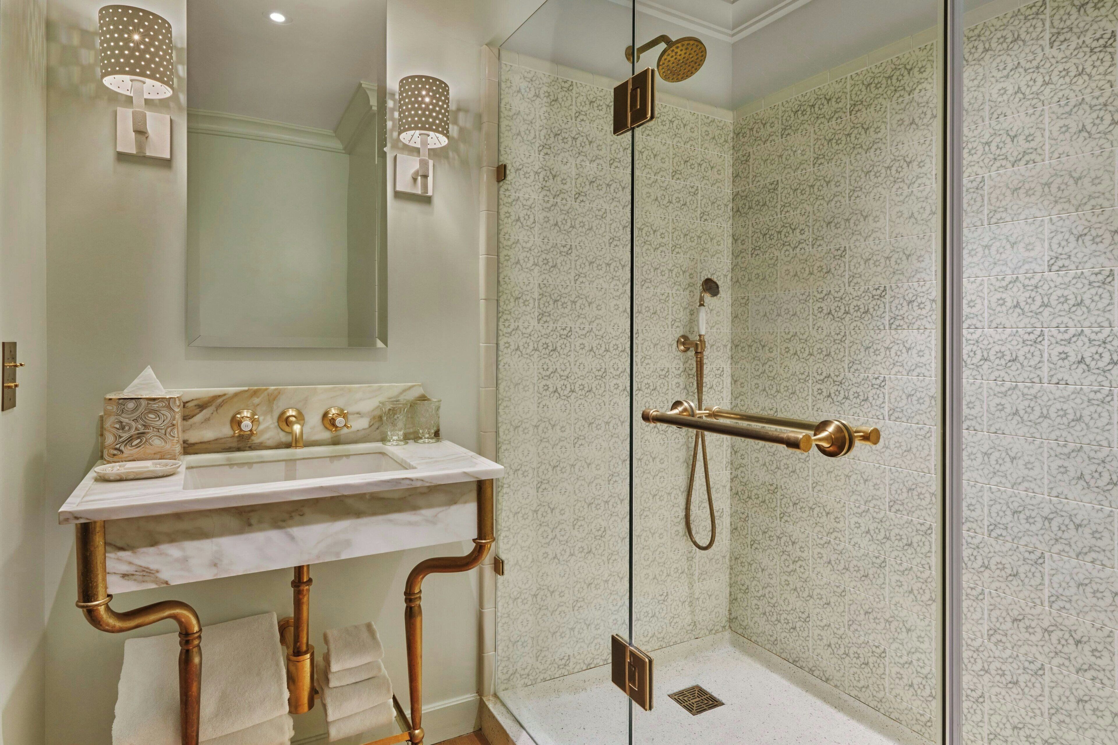 A bathroom with a marble sink, gold fixtures, and patterned tiles.
