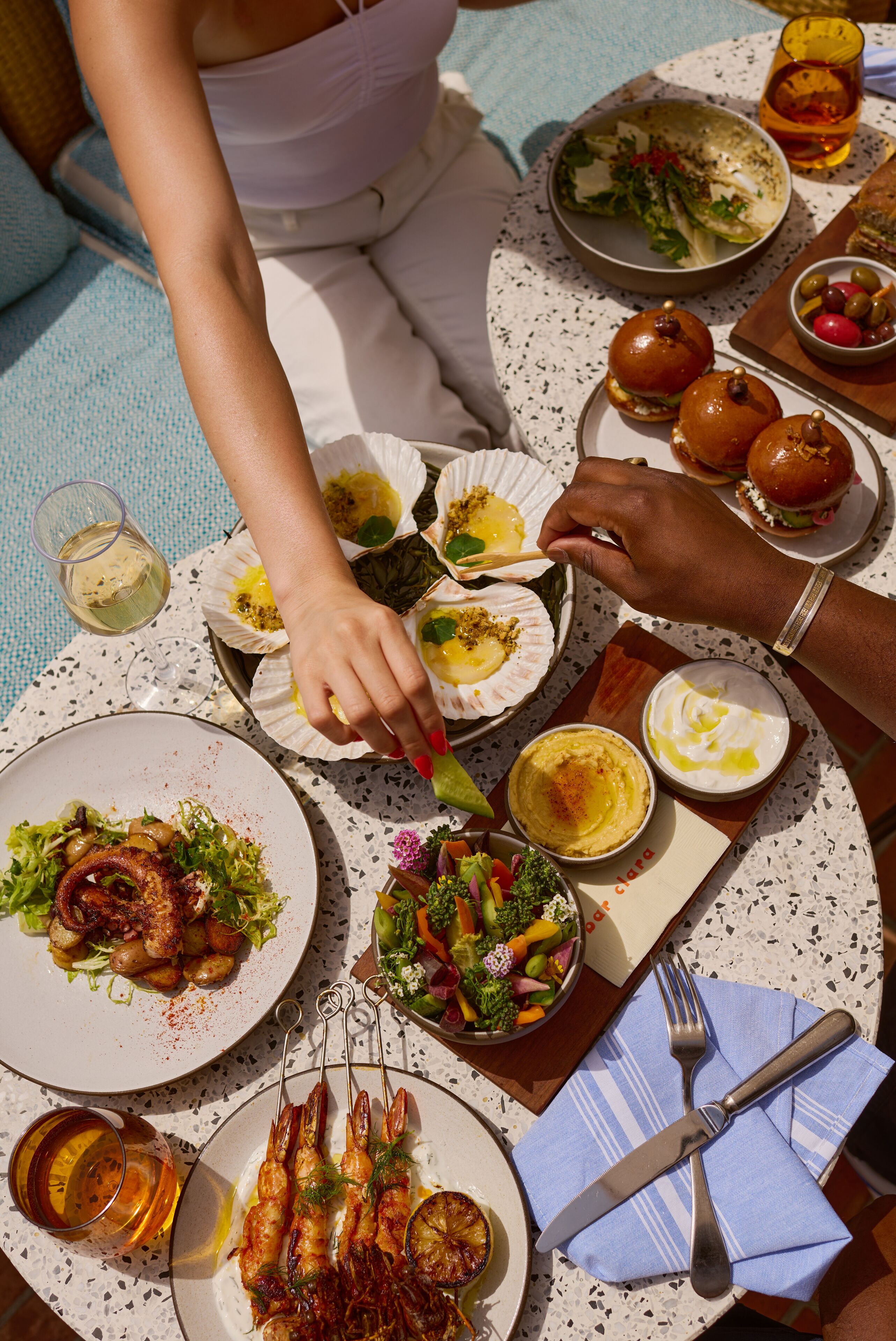 Una mesa dispuesta con diversos platos, incluyendo mariscos, ensaladas y pan, evocando un ambiente para comer.