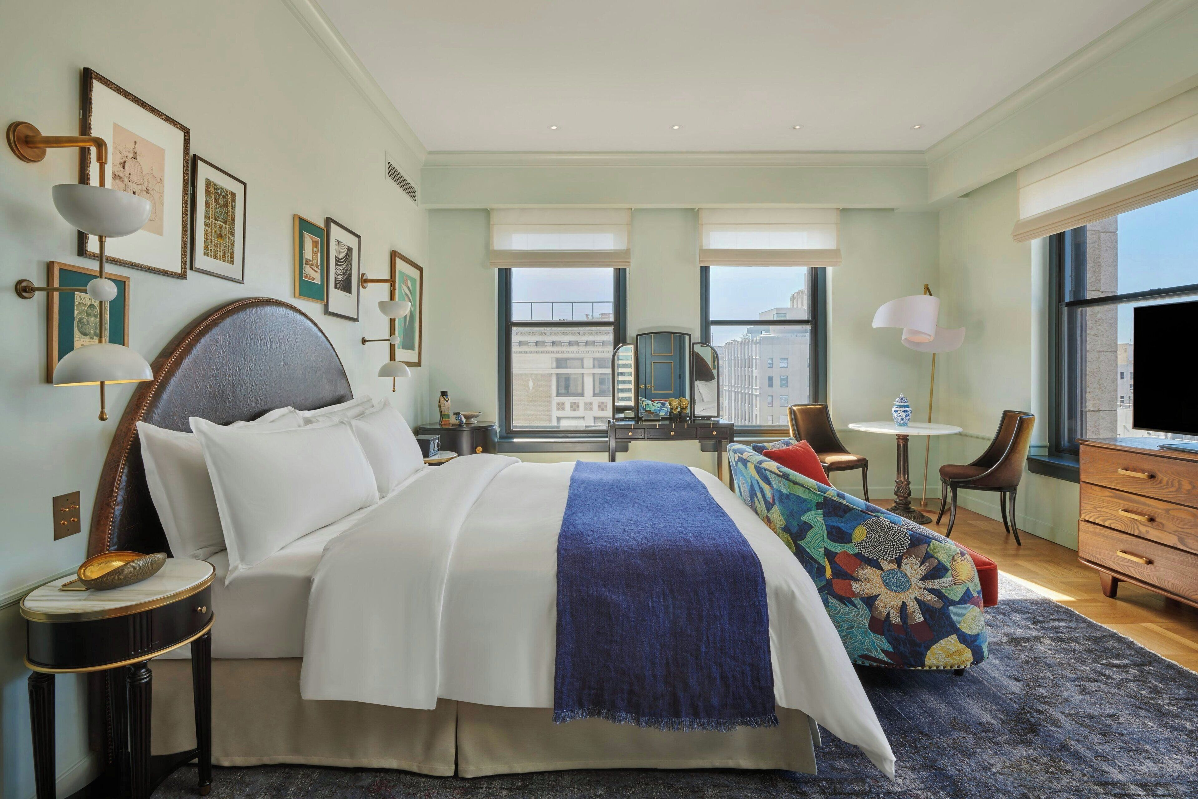 A hotel room with a large bed, a desk, a chair, and a television.