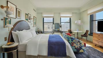 A hotel room with a large bed, a desk, a chair, and a television.