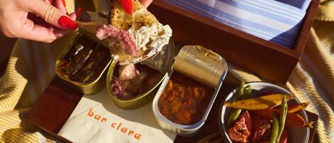 A tray with various food items, including a piece of bread with spread, a bowl of vegetables, and a container of pickles.