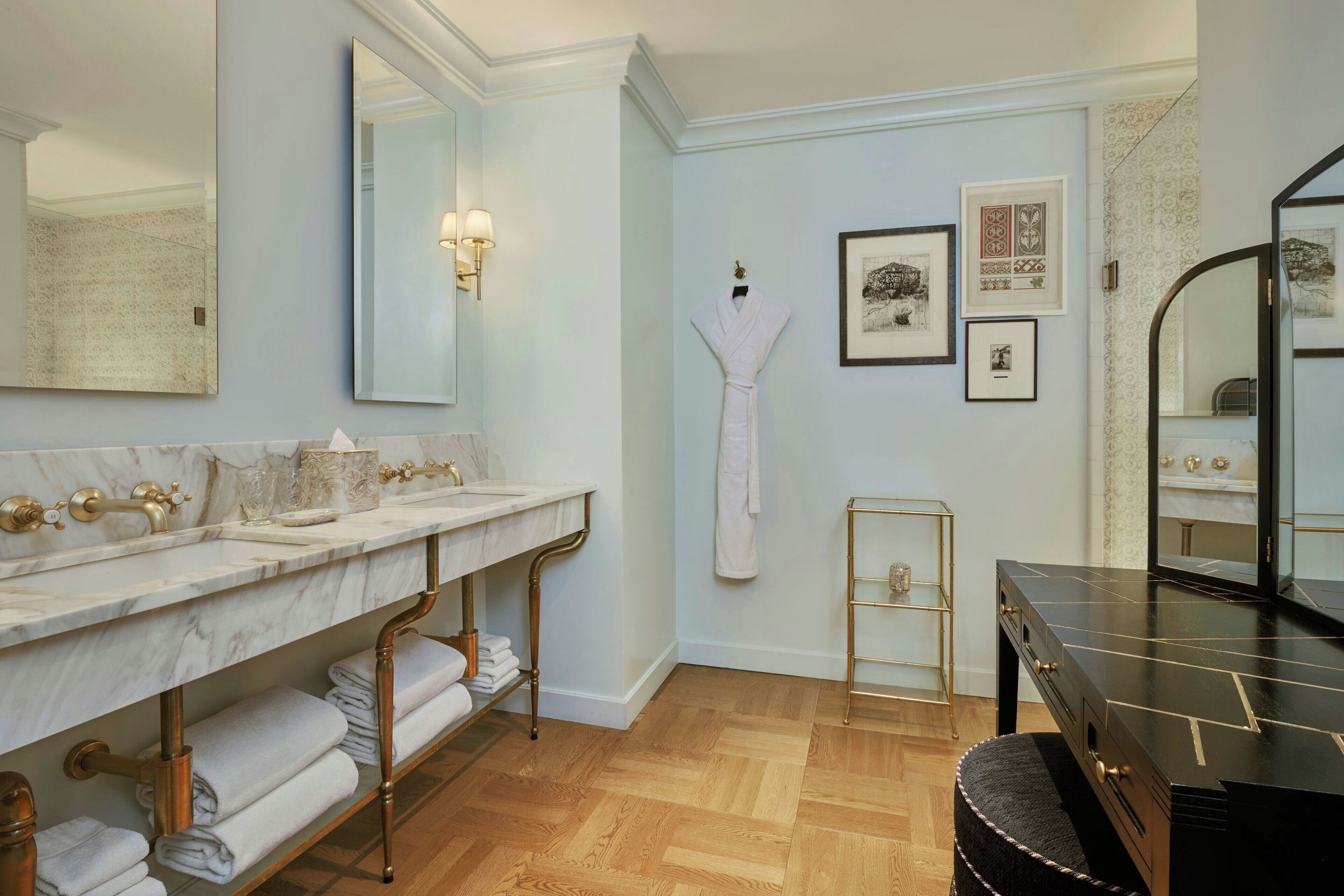 A bathroom with a marble vanity, a large mirror, a robe, and a black vanity.