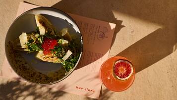 Una comida con ensalada y una bebida sobre una mesa con un menú.