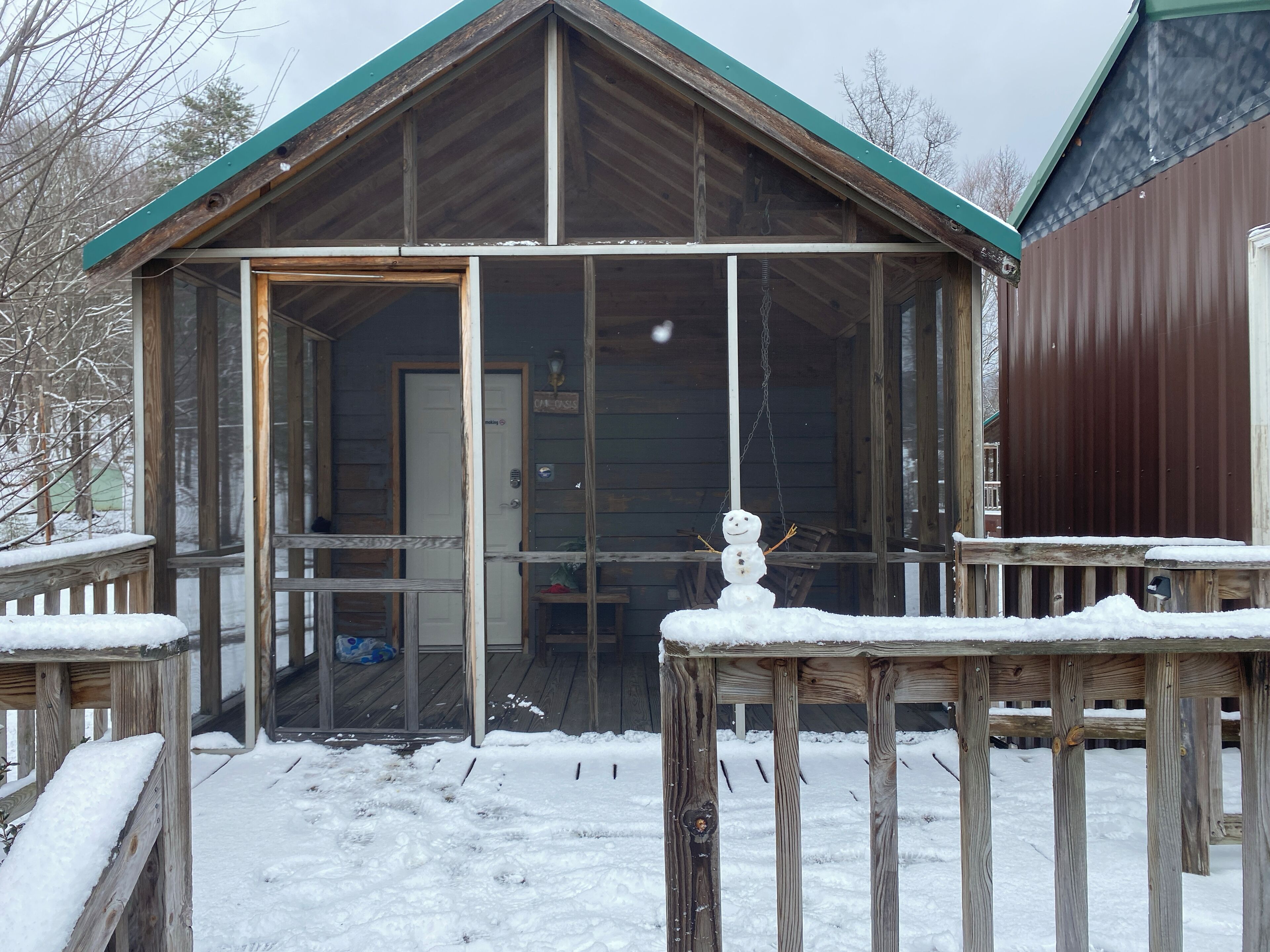 En træhytte med en glasdør, en snefnug-dekoration og en træterrasse.
