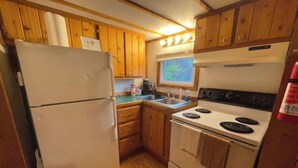 A compact kitchen with wooden cabinets, a white refrigerator, a stove, and a sink. - The Oak Oasis - Gorgeous views and a hot tub (Ansted)