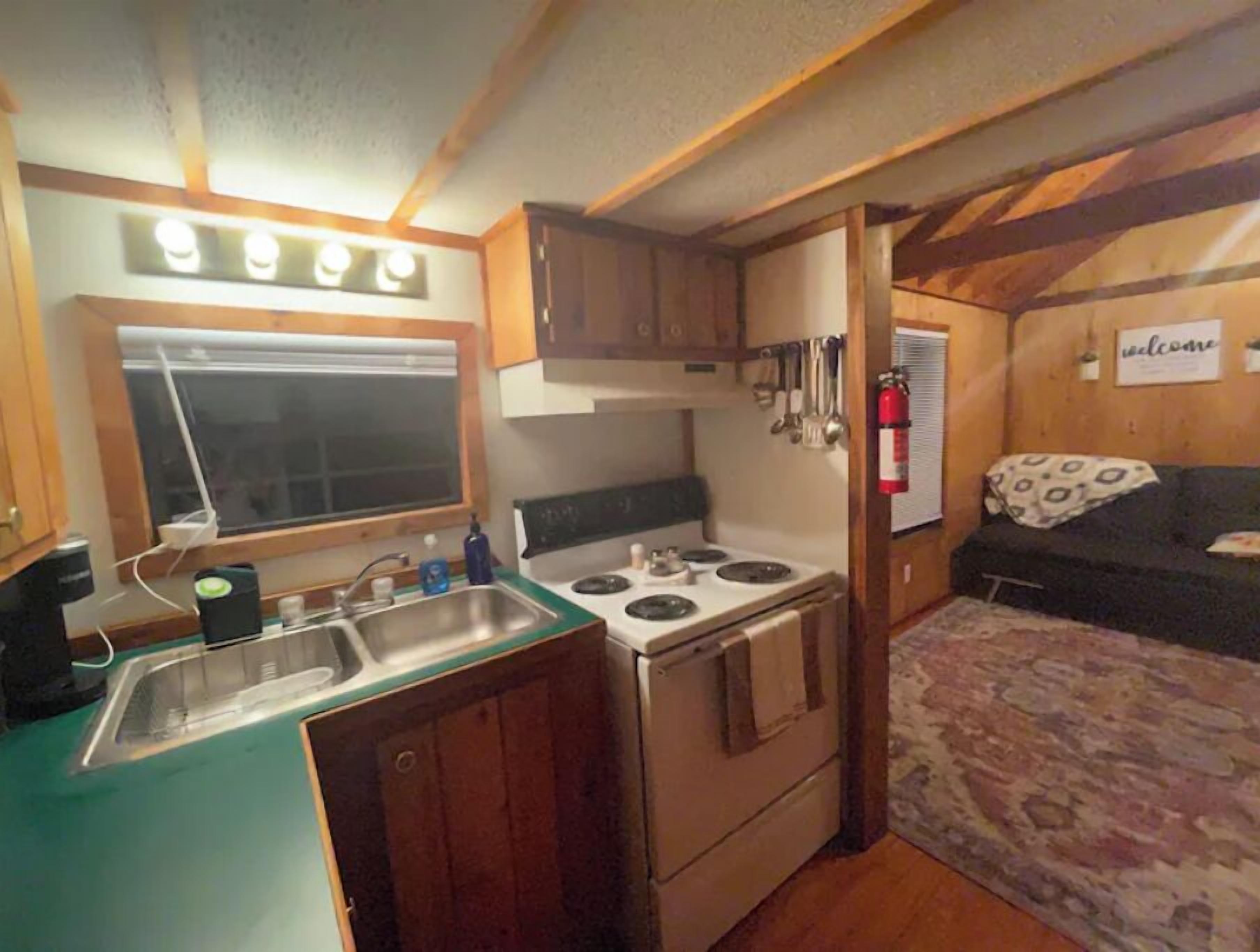 Une cuisine compacte pour camping-car, équipée d’une cuisinière, d’un évier et de placards en bois.