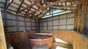 A hot tub in a wooden cabin with a sloped ceiling and wooden walls. - The Oak Oasis - Gorgeous views and a hot tub (Ansted)