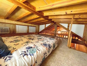 Cozy loft-style bedroom with a large bed and staircase leading to an upper level.