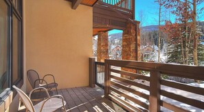 Enjoy breathtaking views of the surrounding mountains from this balcony, featuring a stone pillar and two comfortable chairs.