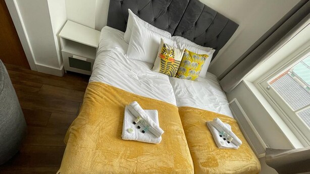 Un letto matrimoniale con copripiumino bianco e giallo, due cuscini a motivo giallo e bianco, e due asciugamani piegati sul letto.