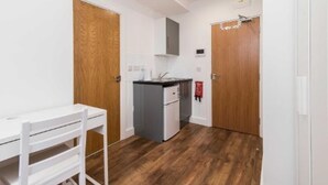 Una piccola cucina accessoriata con frigorifero, lavandino e una porta in legno.