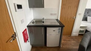 Una piccola cucina compatta con lavandino, un frigorifero e un pensile sopra il lavello.