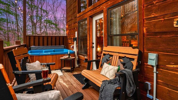 Een houten chalet met een bubbelbad, terras en grote ramen.
